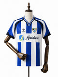 Camisa Málaga - 1º Uniforme Torcedor 2025/26 frente manequim fundo branco